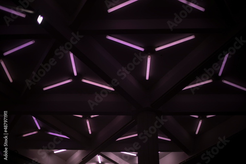 Purple glow of lamps. Fluorescent lamps shine in dark. Background of triangular lamps.