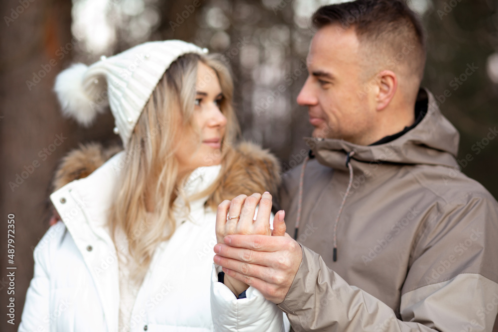 Portrait of happy smiling young couple in casual upper garments stand meeting eyes, holding hands, showing wedding ring. Portrait of happy smiling young couple in casual upper garments stand meeting eyes, holding hands, showing wedding ring.