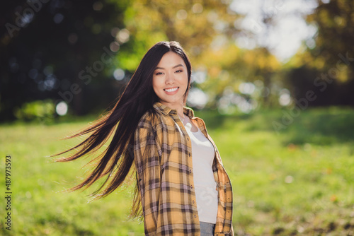 Photo of sweet adorable young lady wear checkered shirt smiling walking outdoors forest clearing