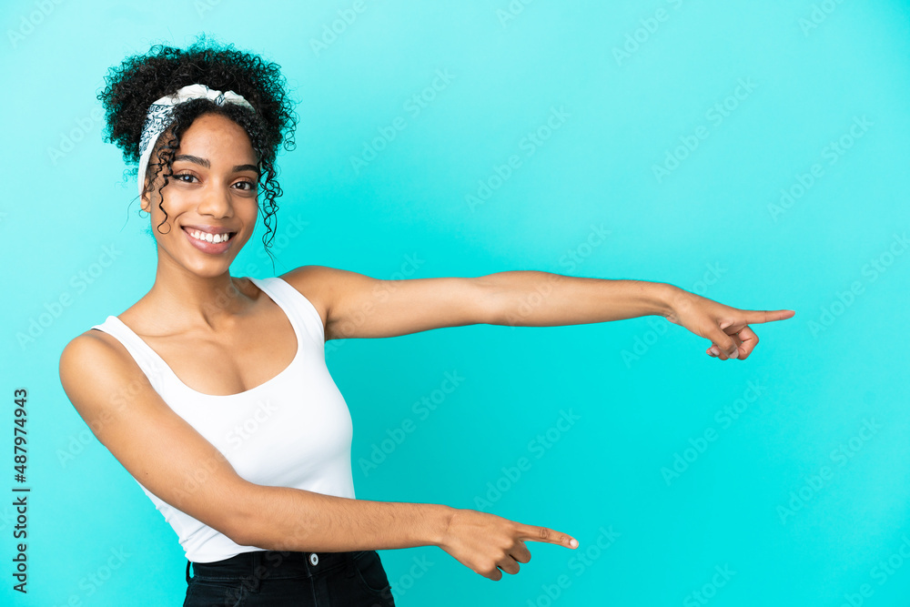 Young latin woman isolated on blue background pointing finger to the side and presenting a product
