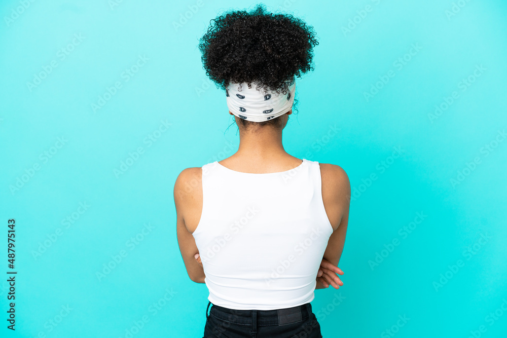 Young latin woman isolated on blue background in back position Young latin woman isolated on blue background in back position