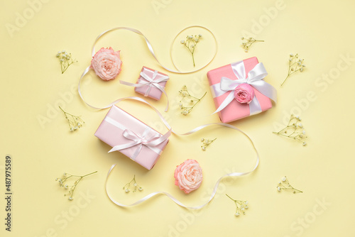 Composition with gifts for International Women's Day and flowers on color background
