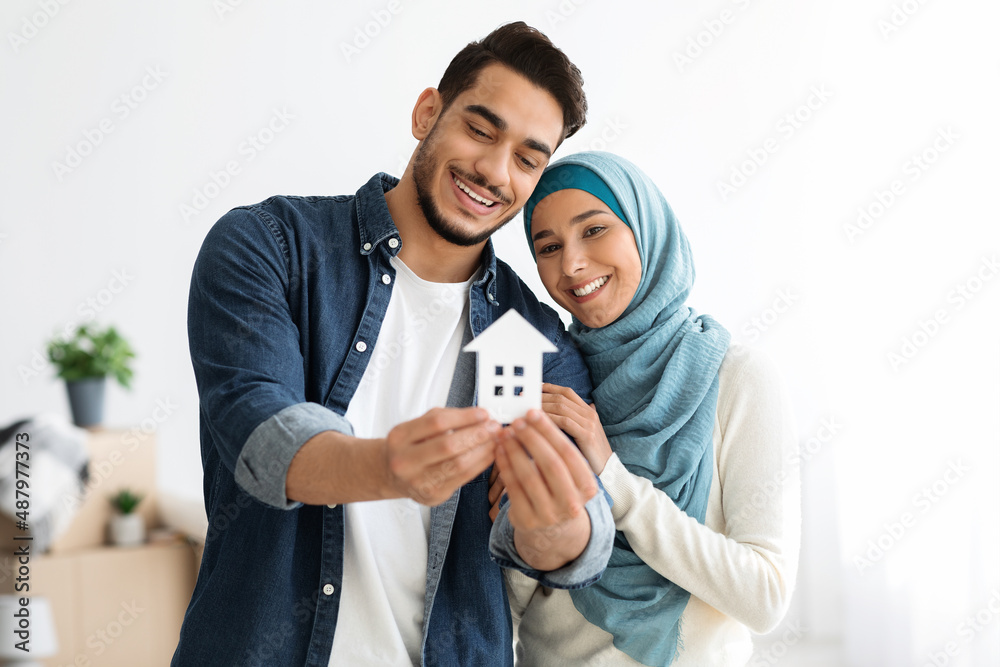 Young loving muslim couple holding paper house and smiling Young loving muslim couple holding paper house and smiling