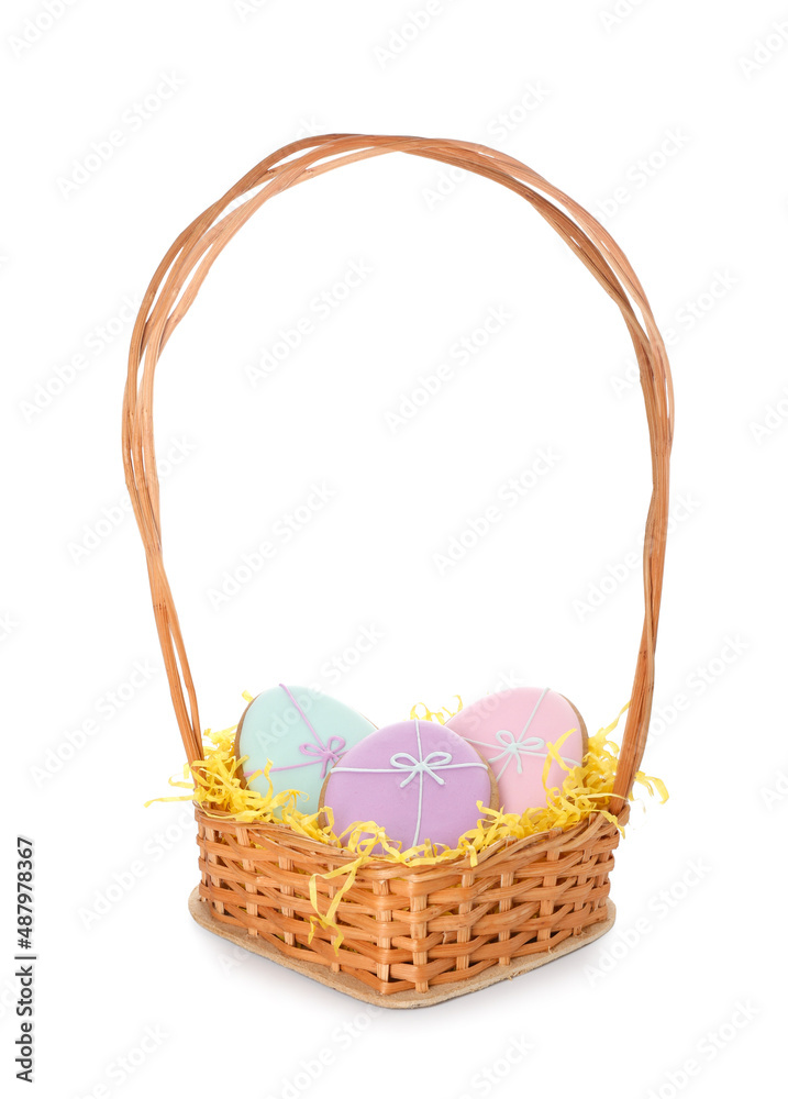 Wicker basket with Easter cookies in shape of eggs on light background