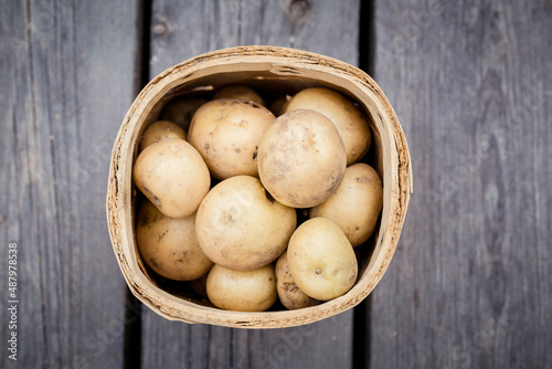 fresh potatoes in a a bsket on wooden backgorund from above photo