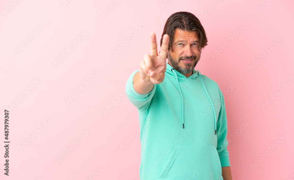 Senior dutch man isolated on pink background smiling and showing victory sign Senior dutch man isolated on pink background smiling and showing victory sign