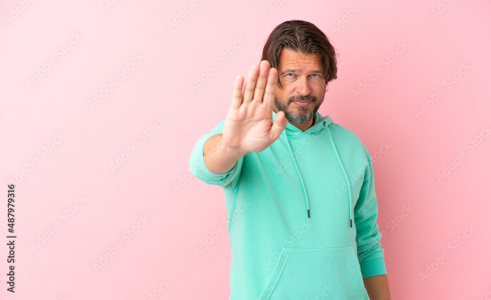 Senior dutch man isolated on pink background making stop gesture Senior dutch man isolated on pink background making stop gesture