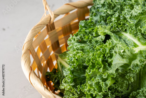 Close-up kale leaves lie in a wooden wicker basket, close-up. photo