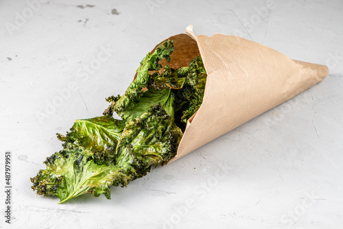 Kale chips in a paper bag on a light background. photo