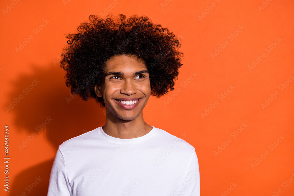 Photo of dreamy cute guy dressed white shirt smiling looking empty space isolated orange color background Photo of dreamy cute guy dressed white shirt smiling looking empty space isolated orange color background