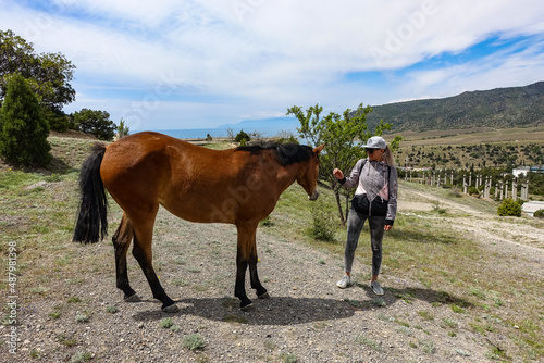 A girl and a young horse near the Kara-Dag mountain. Crimea. Russia 2021