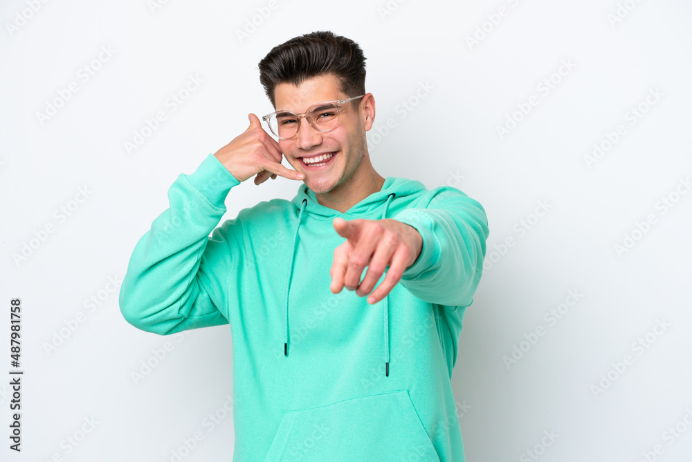 Young handsome caucasian man isolated on white bakcground making phone gesture and pointing front Young handsome caucasian man isolated on white bakcground making phone gesture and pointing front