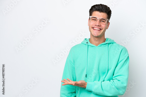 Young handsome caucasian man isolated on white bakcground presenting an idea while looking smiling towards © luismolinero