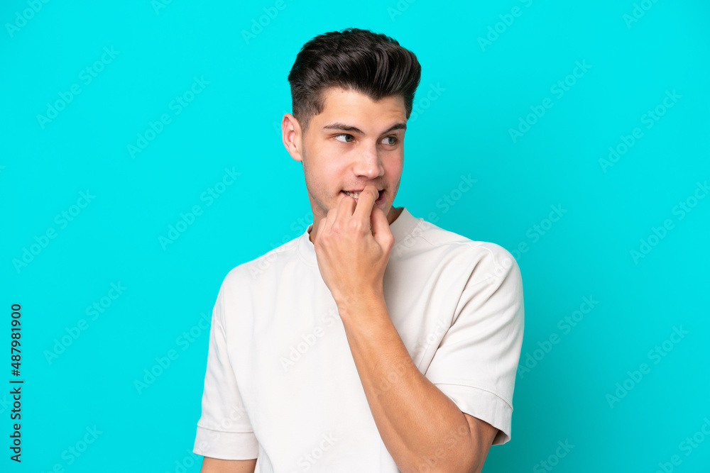 Young handsome caucasian man isolated on blue bakcground nervous and scared