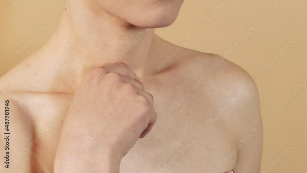 Close-up of a caucasian girl with smooth skin stroking her shoulders with her hand isolated on a beige studio background. Skin care concept. Close-up of a caucasian girl with smooth skin stroking her shoulders with her hand isolated on a beige studio background. Skin care concept.