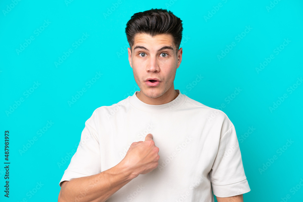 Young handsome caucasian man isolated on blue bakcground pointing to oneself