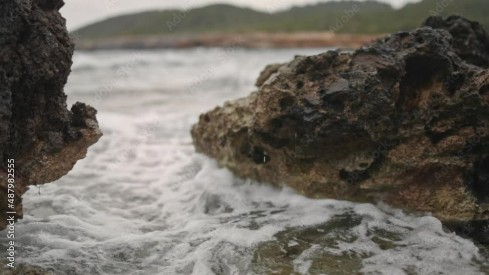Waves crashing between rocks on the beach, slow motion medium shot Waves crashing between rocks on the beach, slow motion medium shot