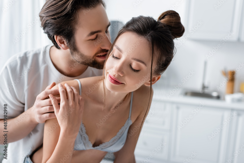 Fototapeta premium bearded man embracing and whispering to young pretty woman in bra at home.