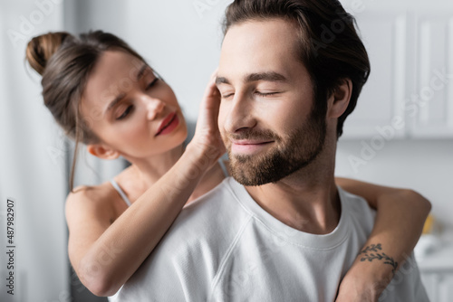 blurred young woman with tattoo hugging pleased man in white t-shirt. © LIGHTFIELD STUDIOS