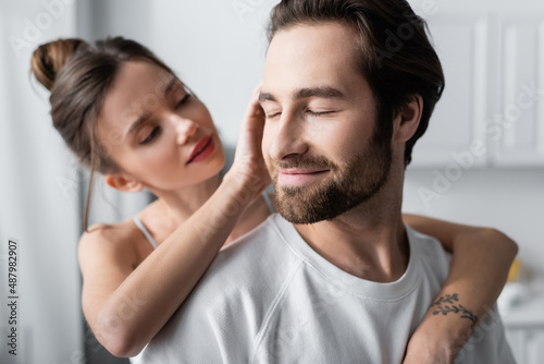 blurred young woman with tattoo hugging pleased man in white t-shirt.