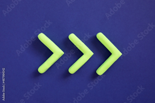 Obraz na płótnie Green arrows pointing right side. Three dimensional arrow sign showing direction on blue background. Development concept, go green or heading target metaphor, striving for the goal, going forward. w salonie