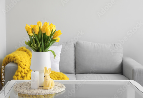 Canvas Vase with tulips, candle and Easter rabbit on table in modern living room