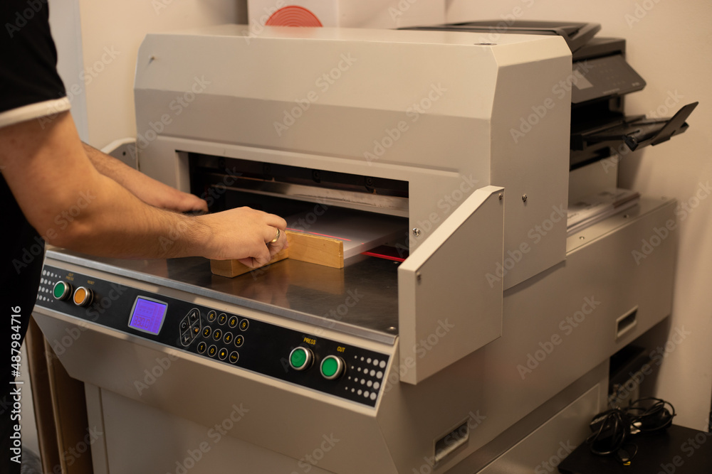 Cropped image man worker hands paper cutter machine, guillotine offset. Level stack papers tray pusher. Manufacture Cropped image man worker hands paper cutter machine, guillotine offset. Level stack papers tray pusher. Manufacture