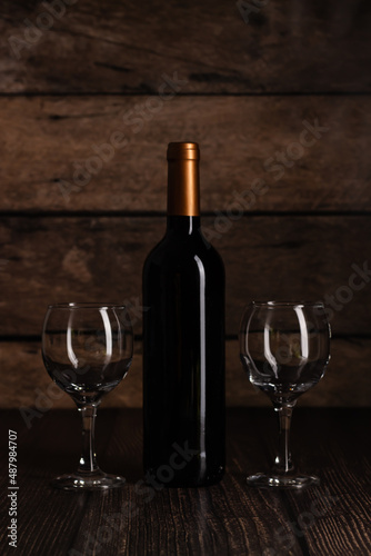 Wine set with bottle and glasses on rustic wooden table, suitable for restaurant and bar promotions.