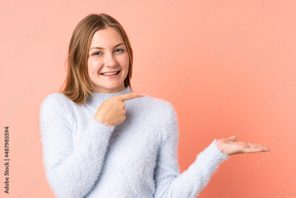 Teenager Ukrainian girl isolated on pink background holding copyspace imaginary on the palm to insert an ad Teenager Ukrainian girl isolated on pink background holding copyspace imaginary on the palm to insert an ad