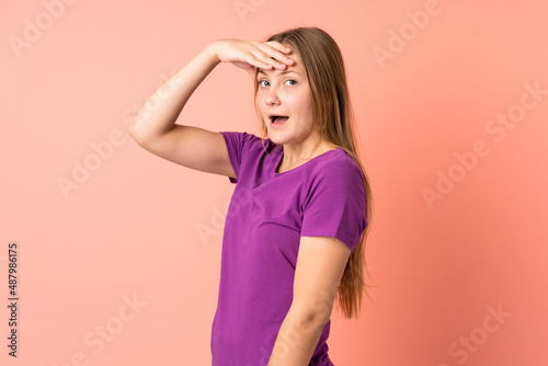 Teenager Ukrainian girl isolated on pink background doing surprise gesture while looking to the side