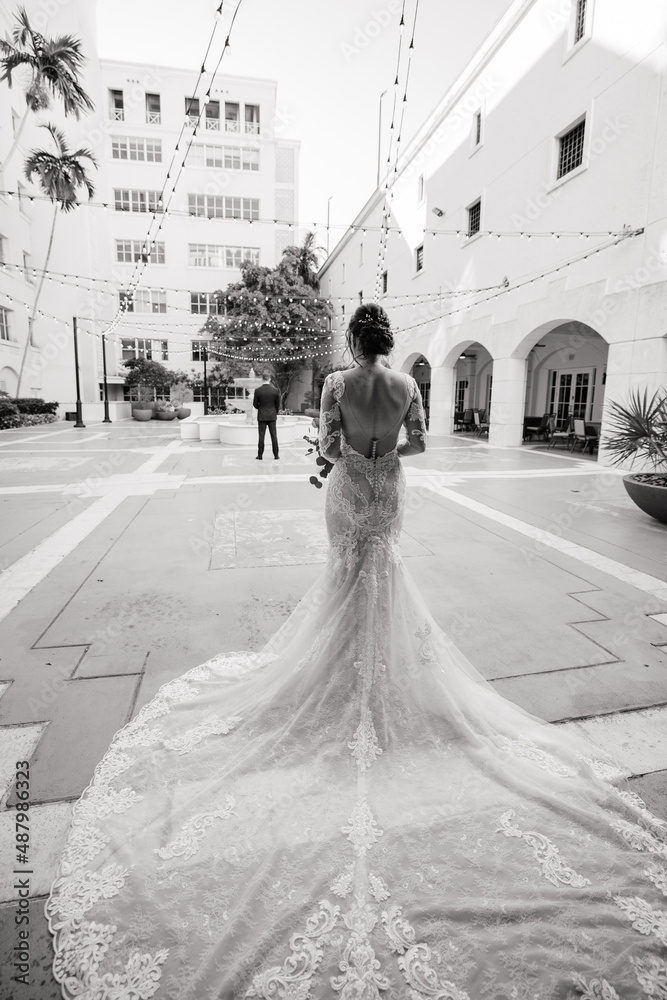 Obraz premium The First meet of the bride in a white gown and groom in a black suit outdoors Groom waits for his beloved Outdoors Cropped photo Black & White photo Back view