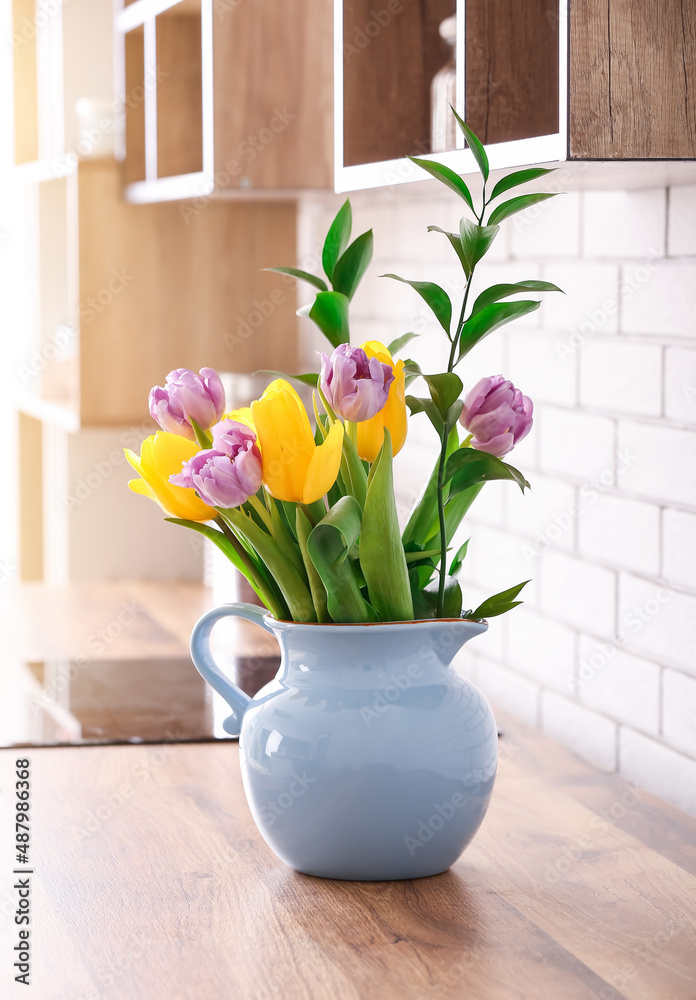 Bouquet of tulips on kitchen counter near white brick wall