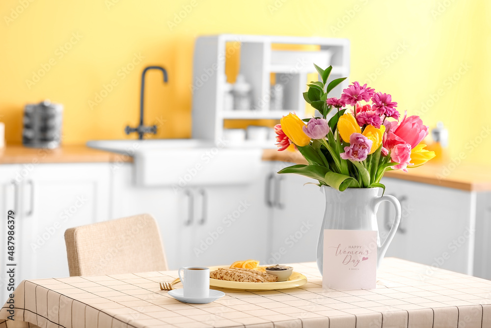 Beautiful flowers, breakfast and greeting card with text HAPPY WOMEN'S DAY on dining table