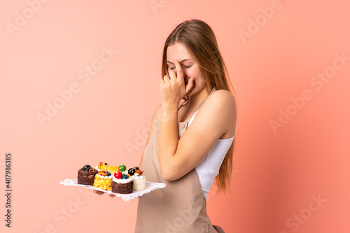 Pastry Ukrainian chef holding a muffins isolated on pink background laughing