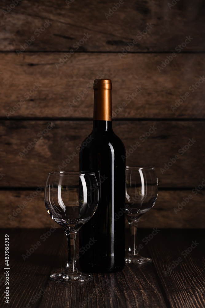 Classic presentation of a wine bottle and glasses on a wooden backdrop, perfect for beverage ads.