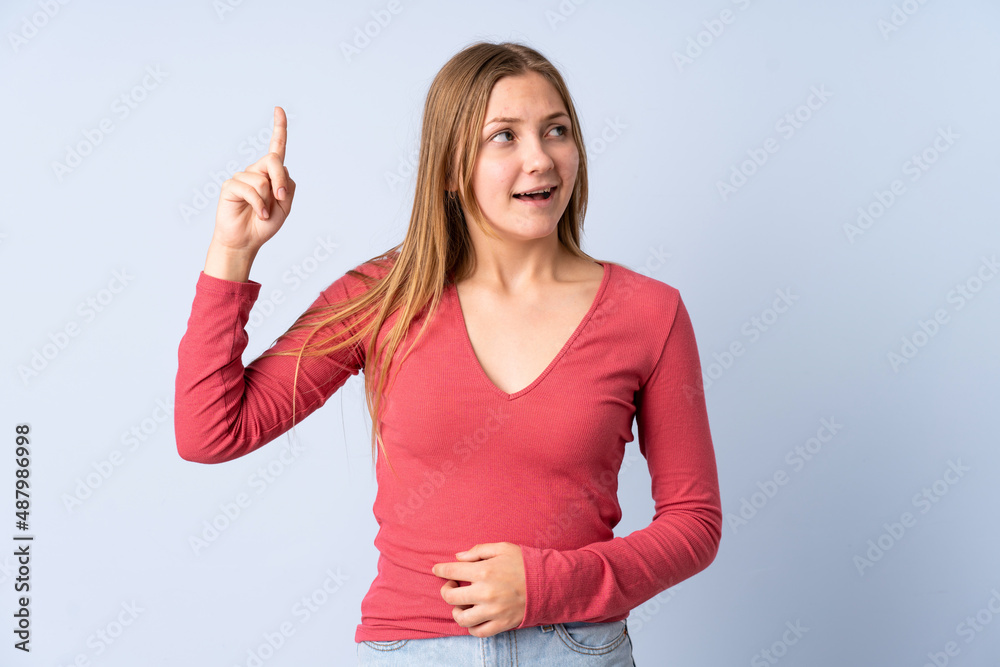 Teenager Ukrainian girl isolated on blue background intending to realizes the solution while lifting a finger up Teenager Ukrainian girl isolated on blue background intending to realizes the solution while lifting a finger up
