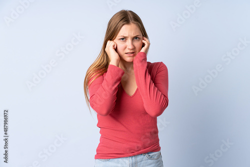 Teenager Ukrainian girl isolated on blue background frustrated and covering ears