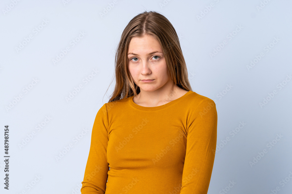 Obraz premium Teenager Ukrainian girl isolated on blue background with sad expression