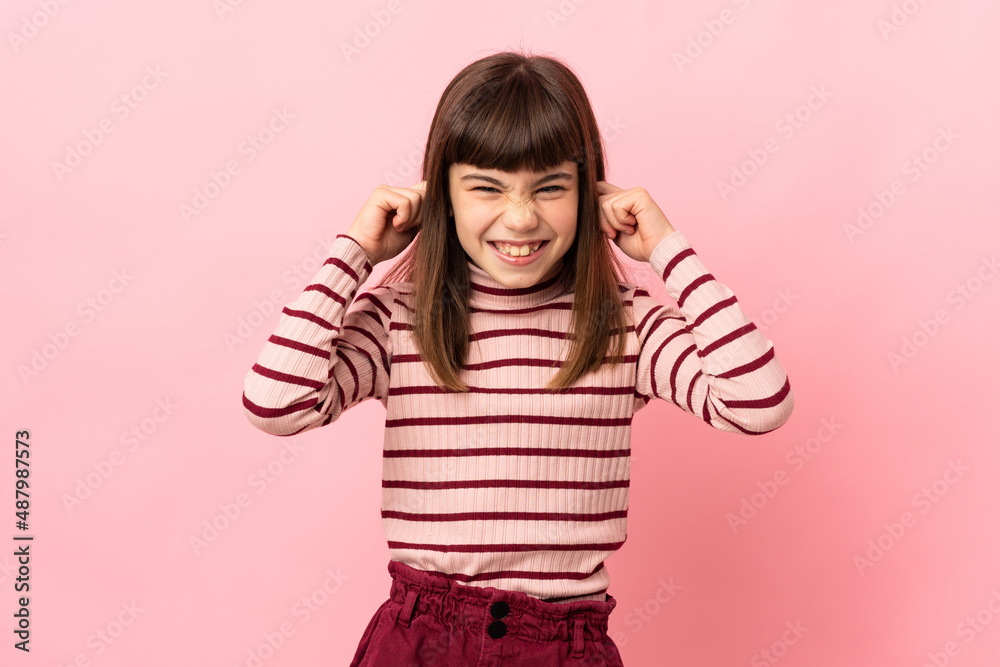 Little girl isolated on pink background frustrated and covering ears