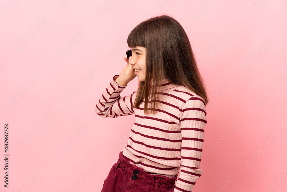 Little girl isolated on pink background keeping a conversation with the mobile phone with someone Little girl isolated on pink background keeping a conversation with the mobile phone with someone