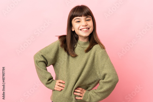 Little girl isolated on pink background posing with arms at hip and smiling © luismolinero