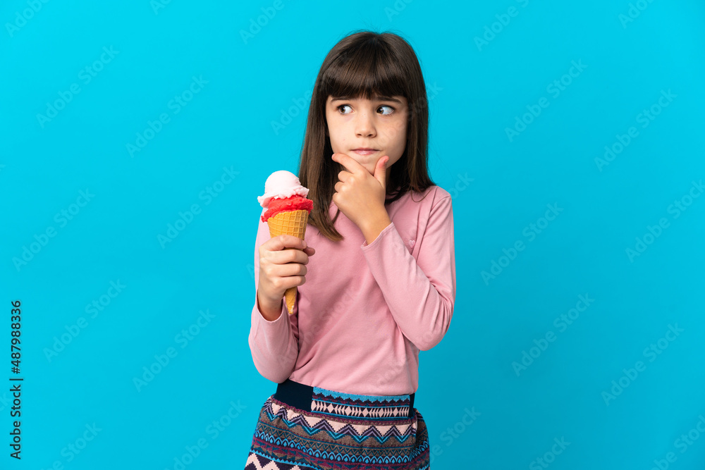Little girl with a cornet ice cream isolated on blue background having doubts and thinking Little girl with a cornet ice cream isolated on blue background having doubts and thinking