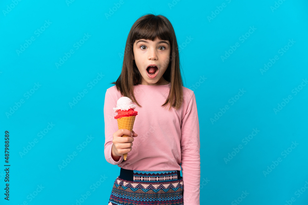 Little girl with a cornet ice cream isolated on blue background with surprise facial expression Little girl with a cornet ice cream isolated on blue background with surprise facial expression