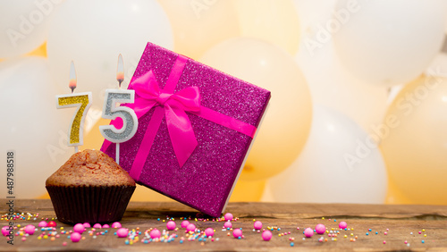 Happy birthday with pink gift box for 75 year old woman. Beautiful birthday card with cupcake and burning candle number seventy five