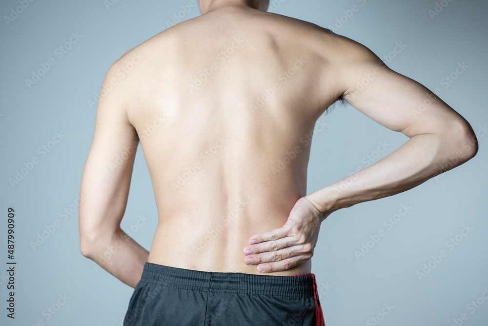Lower back pain, Man holds his hands behind his back pain, Close up.