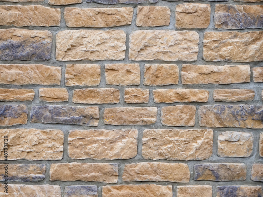 Obraz premium Big stone wall background texture with different colors. Rough weathered surface of a building exterior. Brick pattern of a facade structure with different sized bricks.