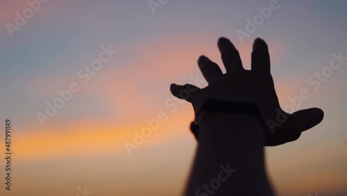 Point of view shot of hand of a man reaching out to the sky during sunset. Man extends his hand towards the sky in search of hope. Hopelessness in a man. Man looking for answers and reaching for sky.