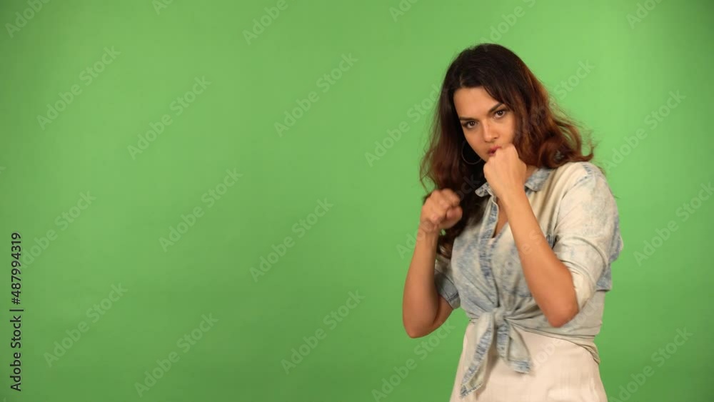 A young beautiful Caucasian woman boxes with the camera - green screen background