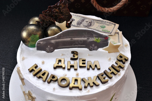 Birthday cake for the man or boy decorated with chocolate balls, dollars, car and golden greetind 