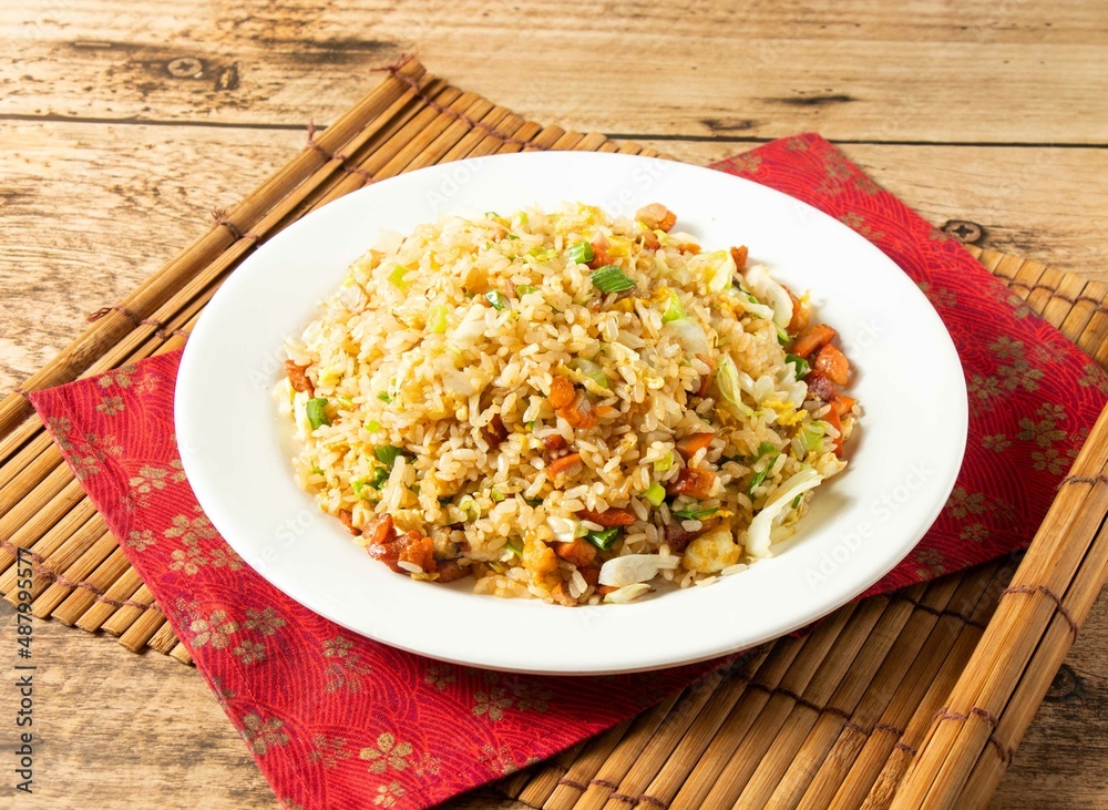 Char Siew Fried Rice in white plate on mat isolated on wooden background top view chinese rice